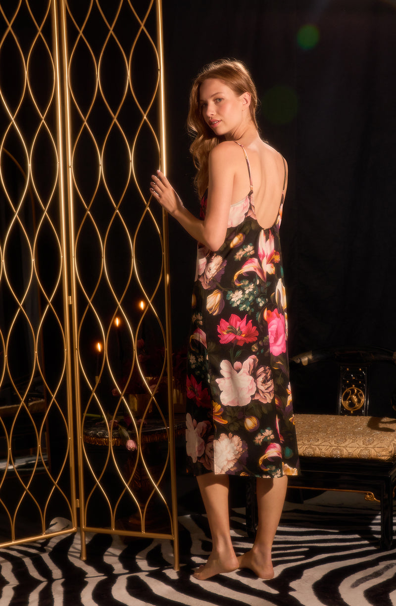 A lady wearing sleeveless Addison Woven Maxi Slip In Midnight Garden with black floral print.